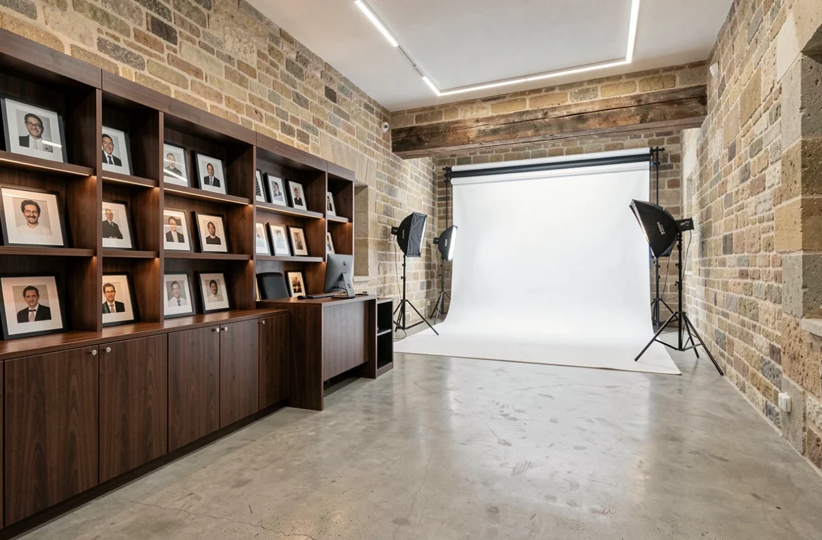Intérieur du Studio Photo Carmes à Toulouse avec murs en pierre apparente, présentoir de portraits encadrés et espace de prise de vue en arrière-plan